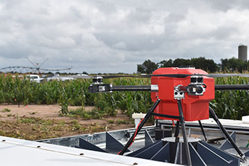 Drone emerging from box in front of corn fields
